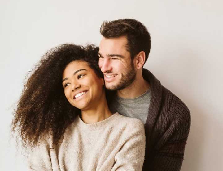 Young couple hugging and smiling and looking away from the camera