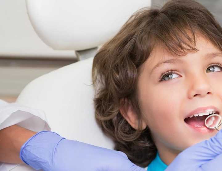 Child in dentist chair looking up at dentist
