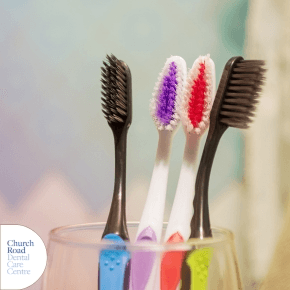 four different coloured toothbrushes in a glass