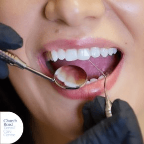 A close up gloved hands showing teeth through a magnifying glass